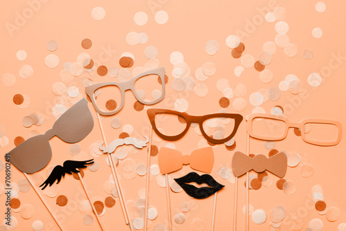 Photo booth props glasses, mustache, lips on a pink background flat lay. New trending PANTONE Peach Fuzz colour of 2024 year (ID: 706902491)