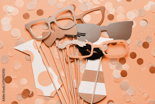 Photo booth props glasses, mustache, lips on a pink background flat lay. New trending PANTONE Peach Fuzz colour of 2024 year (ID: 706902492)