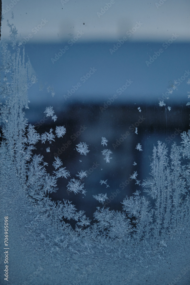 The abstract creation of window frost on window glass. Ornamental floral frost shapes on the window. Frost flowers The abstract creation of window frost on window glass. Ornamental floral frost shapes on the window. Frost flowers
