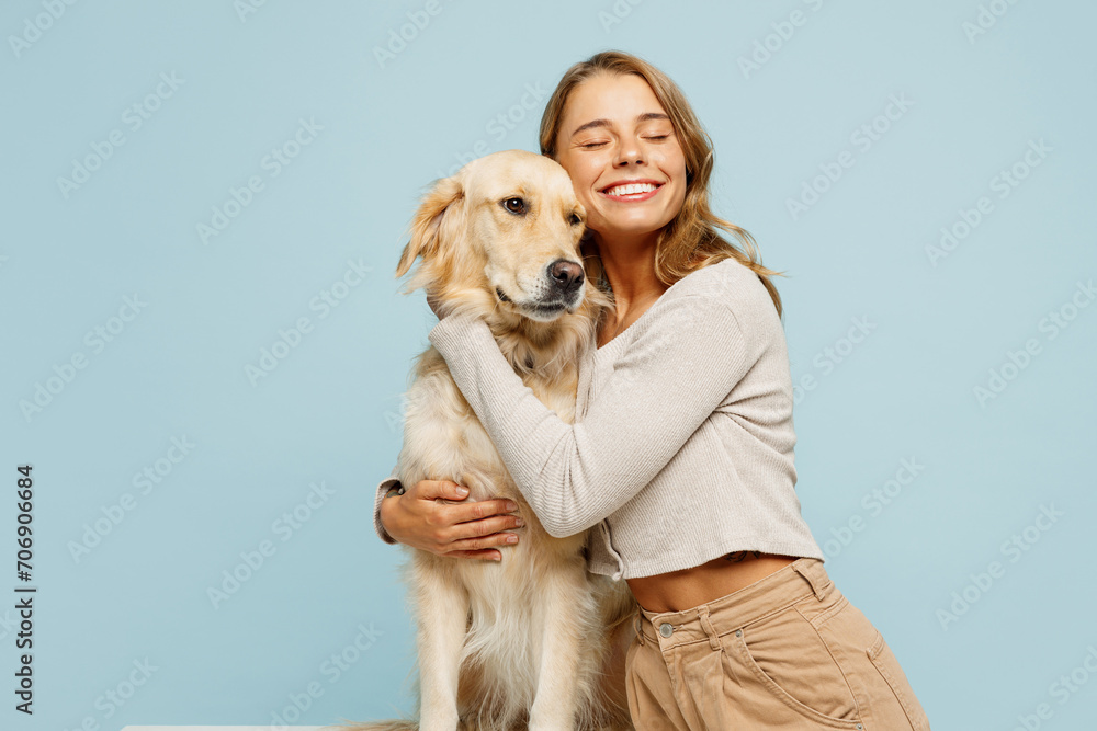 Young smiling cheerful fun owner woman with her best friend retriever wear casual clothes hug embrace dog close eyes isolated on plain pastel light blue background studio. Take care about pet concept - obrazy, fototapety, plakaty 