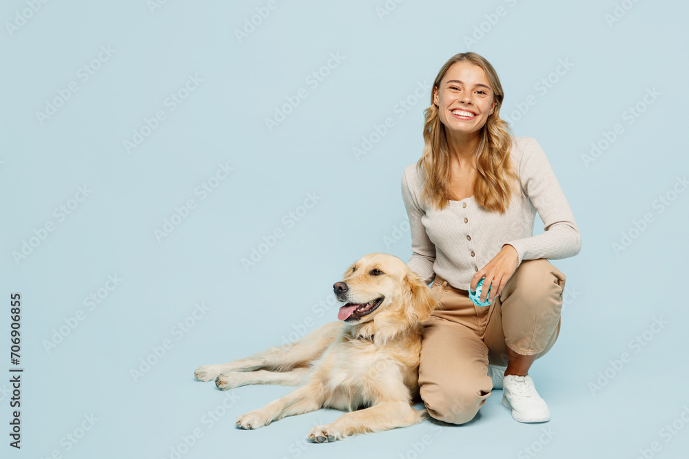 Full body smiling happy young owner woman wearing casual clothes kneeling hug cuddle embrace her best friend retriever dog isolated on plain light blue background studio. Take care about pet concept.