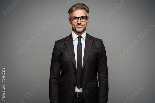 Adult confident attractive serious calm employee business man corporate lawyer wearing classic formal black suit shirt tie work in office look camera isolated on plain grey background studio portrait. photo