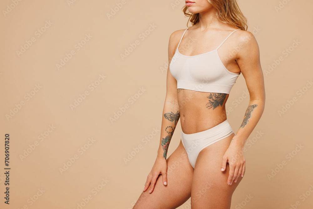 Naklejka premium Close up cropped side view young nice lady woman with slim body perfect skin wear nude top bra lingerie stand put hand on thigs isolated on plain pastel beige background. Lifestyle diet fit concept.
