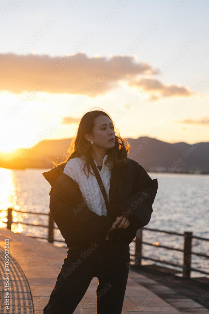 Fototapeta premium 夕暮れの海にいる女性