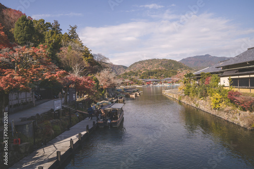 Arashiyama in autumn season along the river in Kyoto, Japan, Aerial view Arashiyama Togetsu or Togetsukyo bridge ancient architecture and boats in Katsura river, Arashiyama, Kyoto, Japan, Asia. © inookphoto