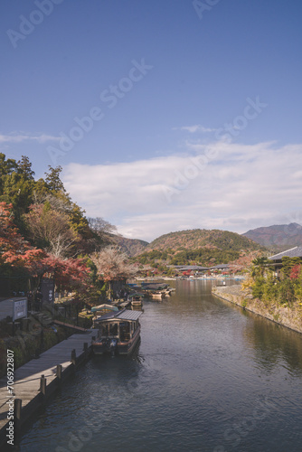 Arashiyama in autumn season along the river in Kyoto, Japan, Aerial view Arashiyama Togetsu or Togetsukyo bridge ancient architecture and boats in Katsura river, Arashiyama, Kyoto, Japan, Asia. © inookphoto