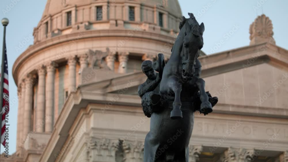 Close up dolly shot of the Tribute to Range Riders statue with the Oklahoma State Capitol building in the background. Close up dolly shot of the Tribute to Range Riders statue with the Oklahoma State Capitol building in the background.