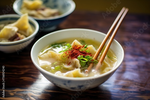 wonton soup garnished with red chili slices photo