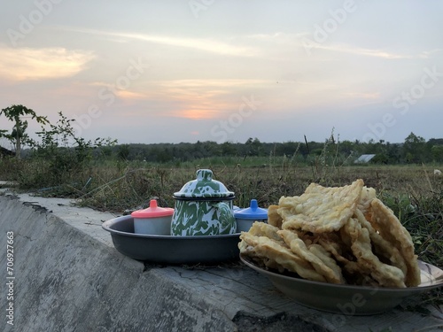 Warm tea and snacks in a serene plantation, perfect for cozy evenings. Tea kettle and cup surrounded by simple fried treats photo