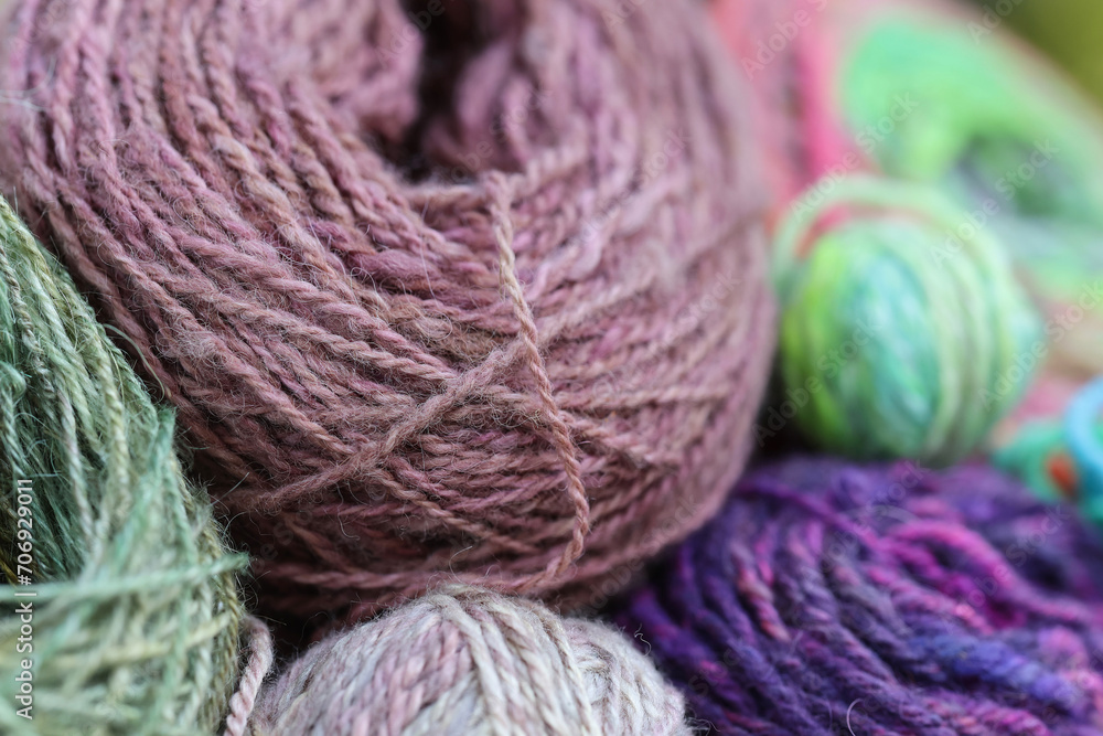 Closeup detail of colourful ball of wool, skeins of organic natural handspun and handdyed merino sheep wool, silk, linnen mix yarn fleece, spun on a traditional spinning wheel Closeup detail of colourful ball of wool, skeins of organic natural handspun and handdyed merino sheep wool, silk, linnen mix yarn fleece, spun on a traditional spinning wheel