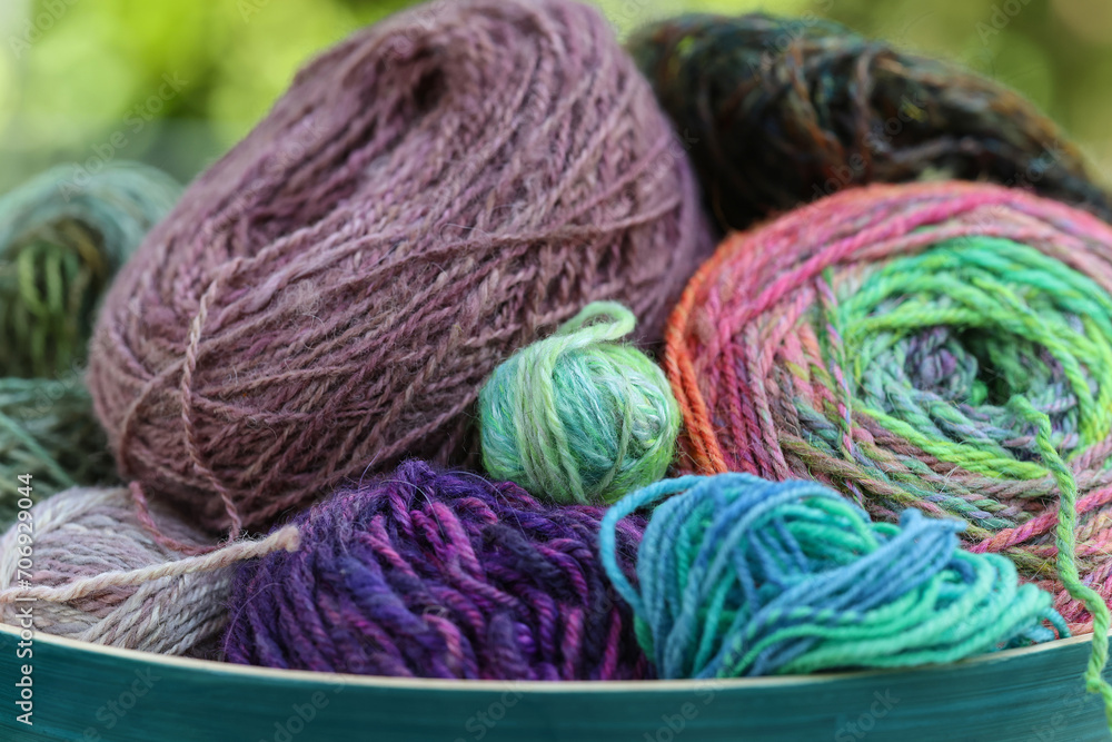 Closeup detail of colourful ball of wool, skeins of organic natural handspun and handdyed merino sheep wool, silk, linnen mix yarn fleece, spun on a traditional spinning wheel Closeup detail of colourful ball of wool, skeins of organic natural handspun and handdyed merino sheep wool, silk, linnen mix yarn fleece, spun on a traditional spinning wheel