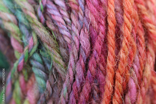 Closeup detail of colourful ball of wool, skeins of organic natural handspun and handdyed merino sheep wool, silk, linnen mix yarn fleece, spun on a traditional spinning wheel