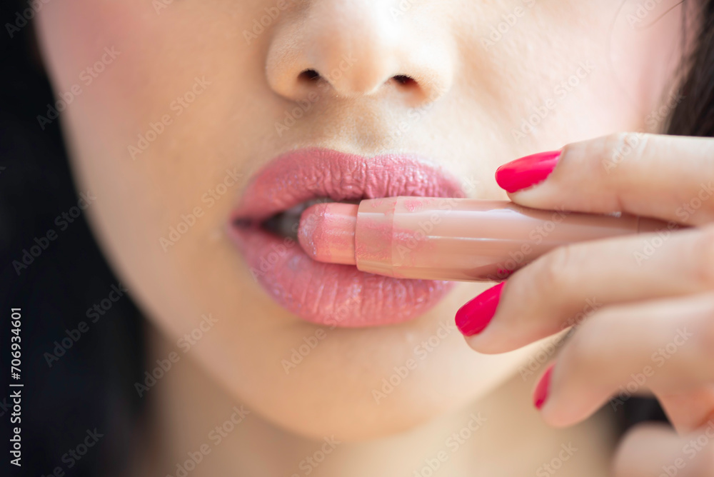 Naklejka premium Young woman applying lip Detail of a beautiful woman applying lipstick