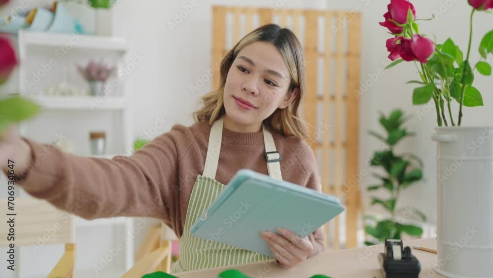 Small business concept. Young asian woman florist using tablet writing on order online at flower shop. Female florist or flower shop owner using tablet working, receiving order at flower shop Small business concept. Young asian woman florist using tablet writing on order online at flower shop. Female florist or flower shop owner using tablet working, receiving order at flower shop