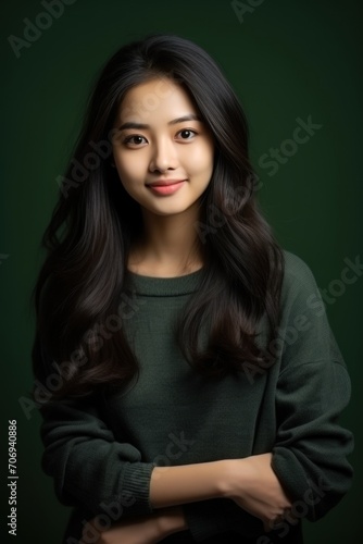 A beautiful Asian teenage girl poses for a straight-faced photo in a studio against a black backdrop. © เลิศลักษณ์ ทิพชัย