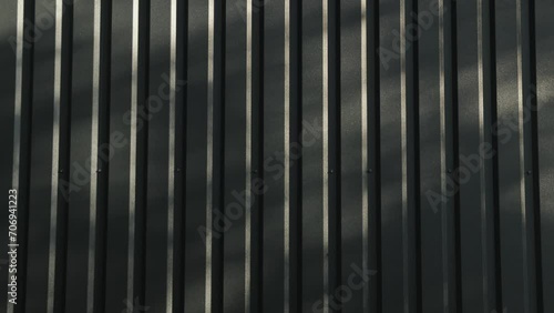 Close-up of outdoor metal wall camera moving forward, shadow from trees over the tiny house in the green forest at summer, Sunlight spots, black metal construction of the house, slow motion photo