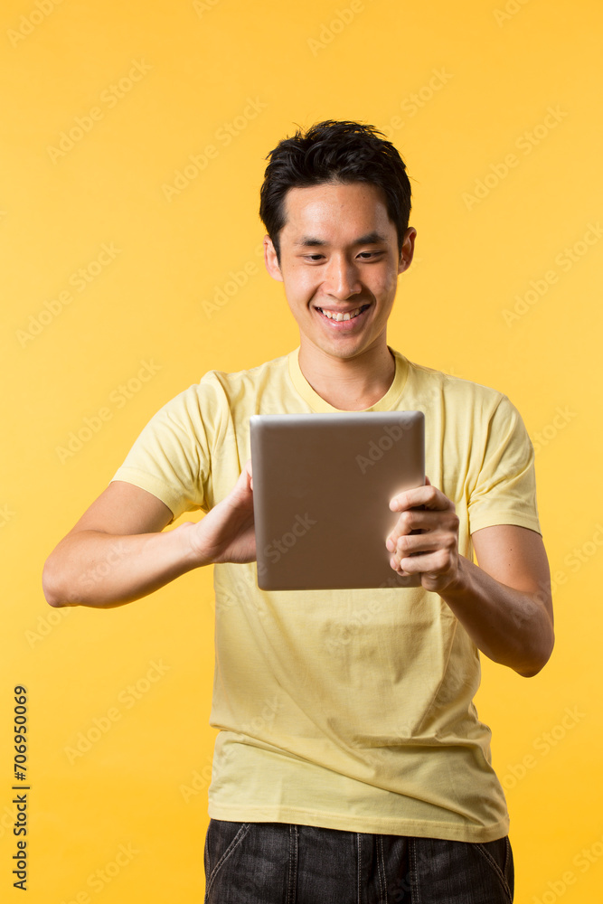 Chinese man using a tablet PC In front of Yellow background. Chinese man using a tablet PC In front of Yellow background.
