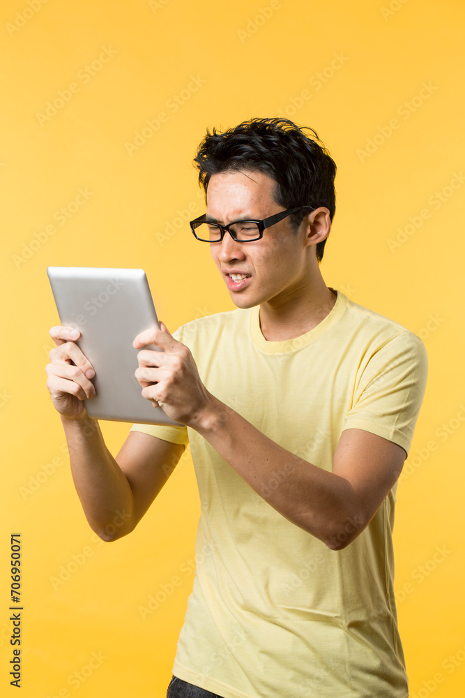 Annoyed Chinese man using Digital tablet. Annoyed Chinese man using Digital tablet.