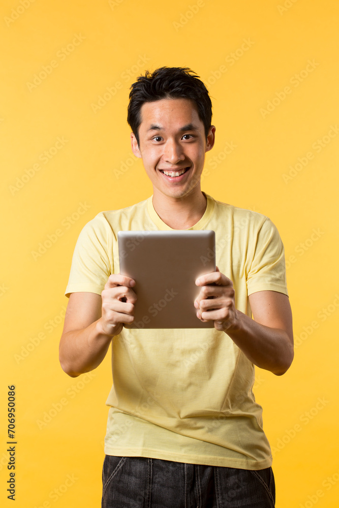 Chinese man using a tablet PC In front of Yellow background. Chinese man using a tablet PC In front of Yellow background.