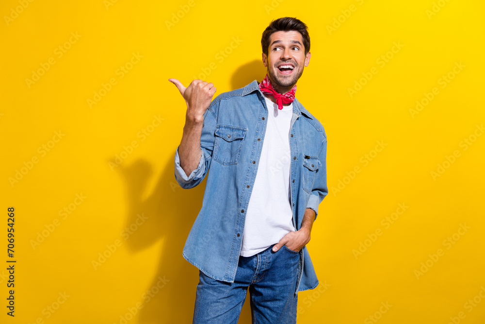 Photo portrait of handsome young guy point look empty space wear trendy jeans outfit isolated on yellow color background Photo portrait of handsome young guy point look empty space wear trendy jeans outfit isolated on yellow color background