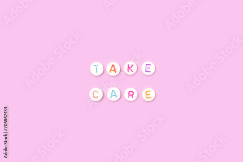 Take care. Quote made of white round beads with multicolored letters on a purple background.