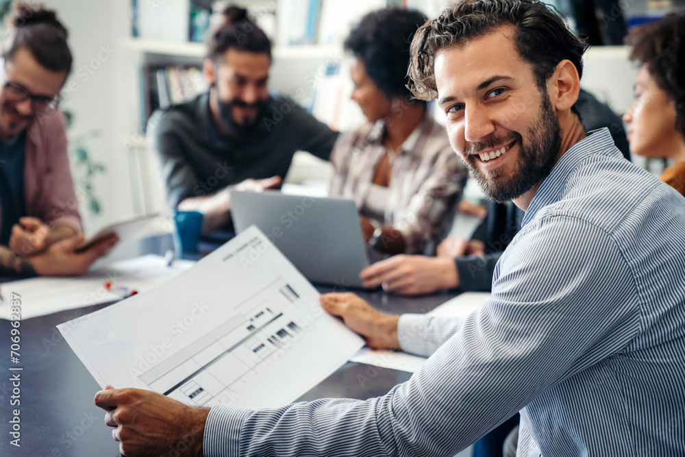 Smiling diverse colleagues gather in boardroom brainstorm discuss financial statistics together Smiling diverse colleagues gather in boardroom brainstorm discuss financial statistics together