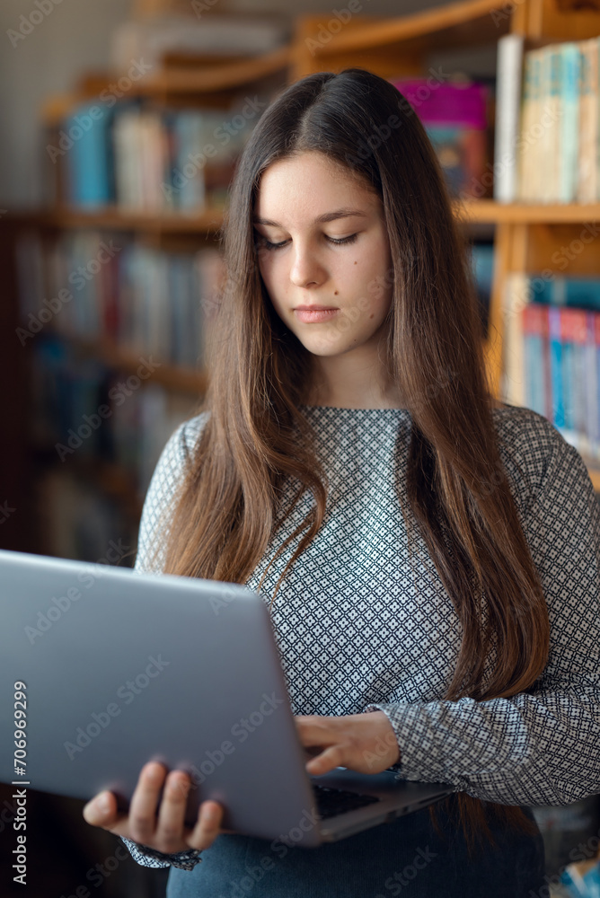 Portrait of a young student with laptop in library. Female learner studying in library, using modern computer, study class assignment Portrait of a young student with laptop in library. Female learner studying in library, using modern computer, study class assignment