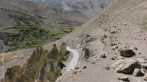 Aerial 4K video by a drone following a 4x4 SUV on the road through the cold desert mountains of Spiti Valley photo