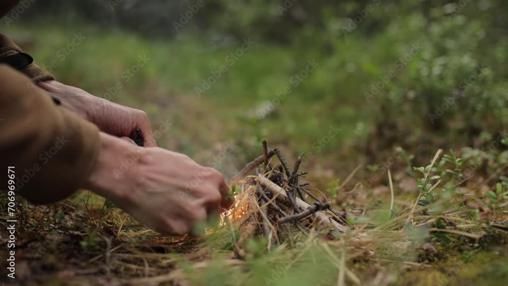 A man in the open air is trying to light a fire with a flint. Survival in the wild A man in the open air is trying to light a fire with a flint. Survival in the wild