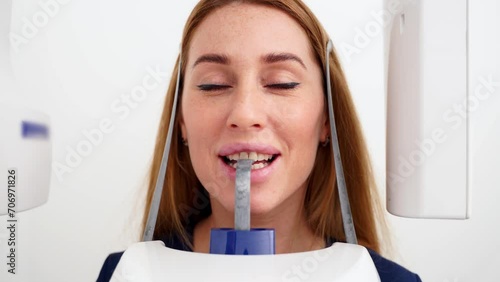 Close-up of woman's face with head positioned in cephalometric panorama x-ray machine. Female patient stands in dental x-ray machine for dental radiography. Woman making panoramic shot of the jaw. photo