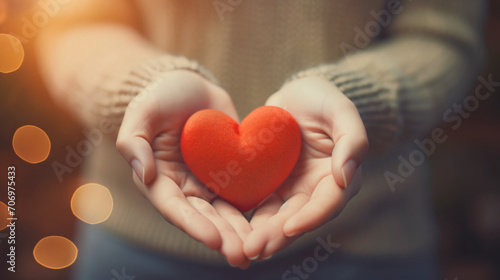 Hands of a woman holding and offering a heart shape