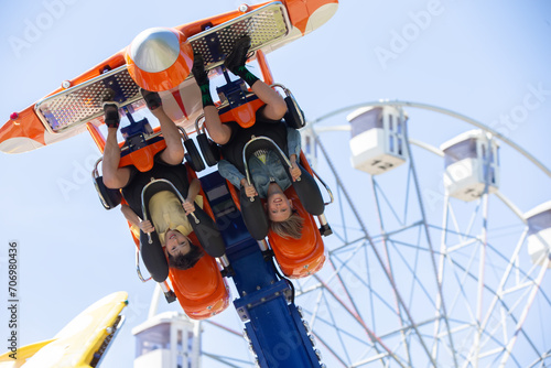 Teenagers ride head down on a carousel. Extreme rides in the park.