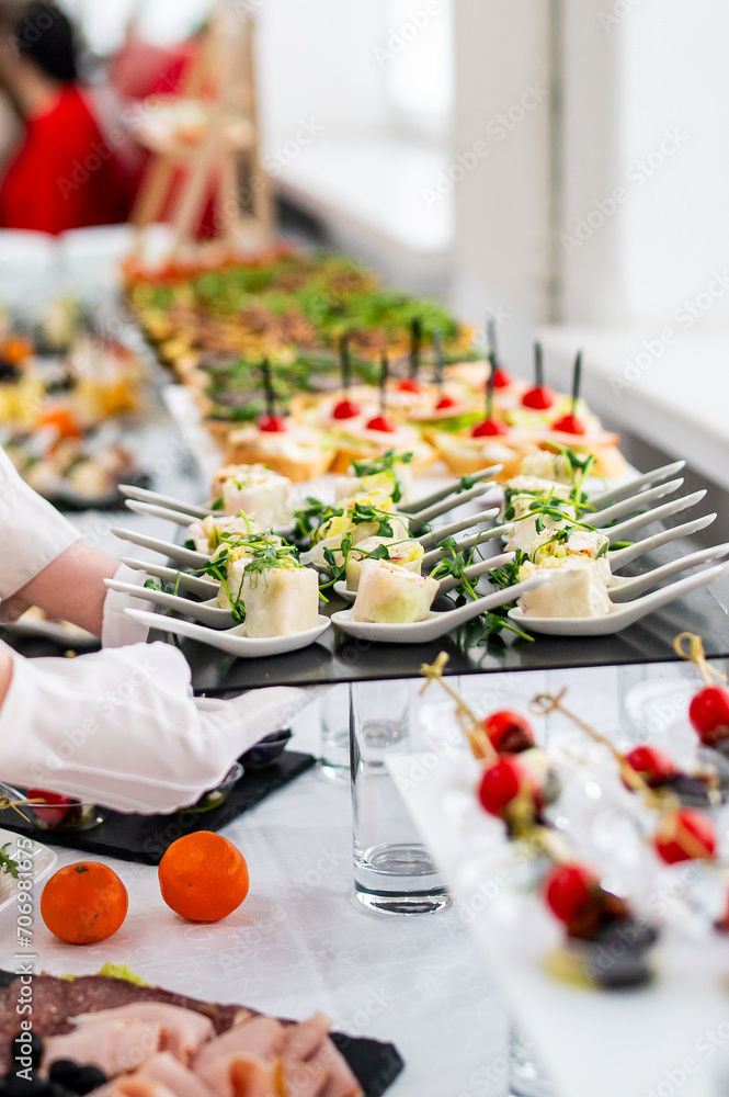 woman hands of a waiter prepare food for a buffet table in a restaurant