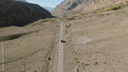 Aerial landscape video by a drone following a black 4x4 suv car in the cold climate rocky high altitude mountains on Spiti Valley. photo