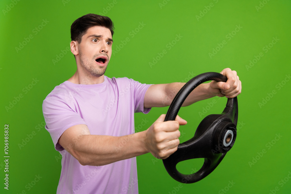 Portrait of astonished person wear t-shirt staring at accident empty space steering wheel in arms isolated on green color background Portrait of astonished person wear t-shirt staring at accident empty space steering wheel in arms isolated on green color background