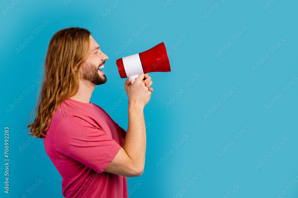 Profile portrait of excited positive person hold loudspeaker toa communicate empty space isolated on blue color background Profile portrait of excited positive person hold loudspeaker toa communicate empty space isolated on blue color background