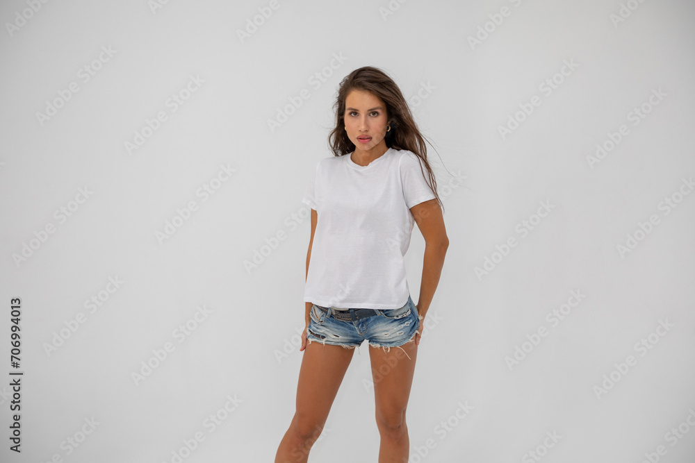 Beautiful brunette girl in a white T-shirt and denim shorts posing Beautiful brunette girl in a white T-shirt and denim shorts posing