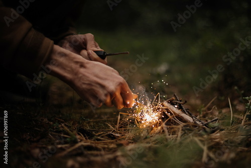Man outdoors makeing fire by flint. Flamethrower. Survival in the wild