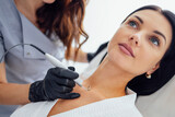 Beautiful caucasian young woman is doing a mole removal procedure in a modern beauty cosmetic dermatological clinic