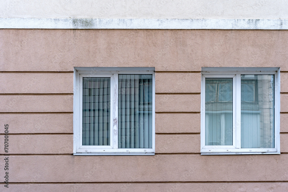 Two white PVC double casement windows. Closed blinds. Two white PVC double casement windows. Closed blinds.
