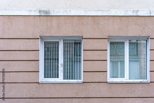 Two white PVC double casement windows. Closed blinds.