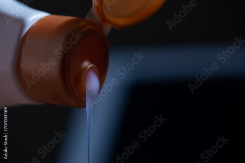 shampoo gel is poured from a plastic container and stream of drops
