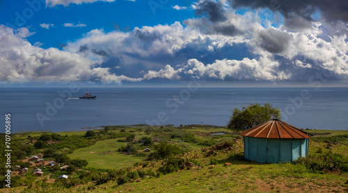 Serene Coastal Landscape with Vibrant Blue Round Building  Lush Greenery  and Calm Sea