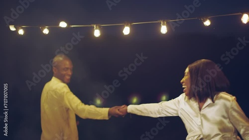 happy african american couple dancing together at party - people on summer night celebrating love and joy