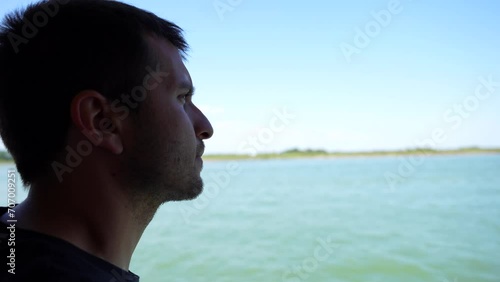Young adult male travelling on calm ocean water to destination unknown photo