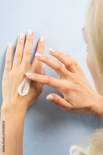 Woman smudging hand or body cream on her hands, body care concept
