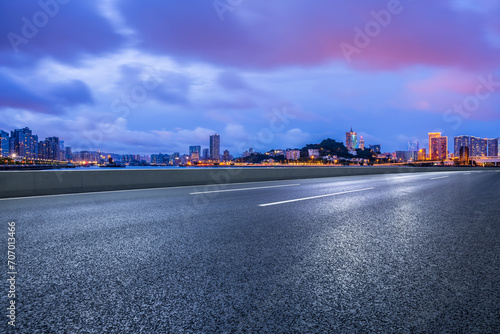 Asphalt highway road and city skyline at night