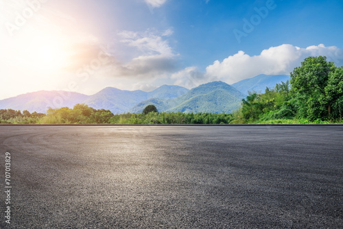 Asphalt road square and green forest with mountain natural landscape under blue sky © ABCDstock