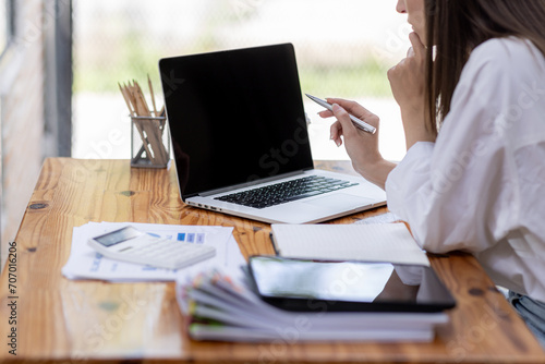 Young business hispanic woman work on laptop desk doing math finance on an office desk, tax, report, accounting, statistics, and analytical research concept © David