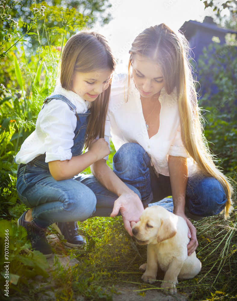 Happy woman and her daughter with puppy of labrador Happy woman and her daughter with puppy of labrador